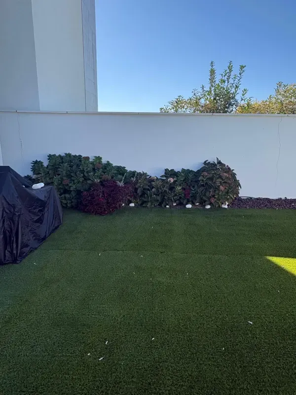Césped artificial junto a parterre con plantas de flor